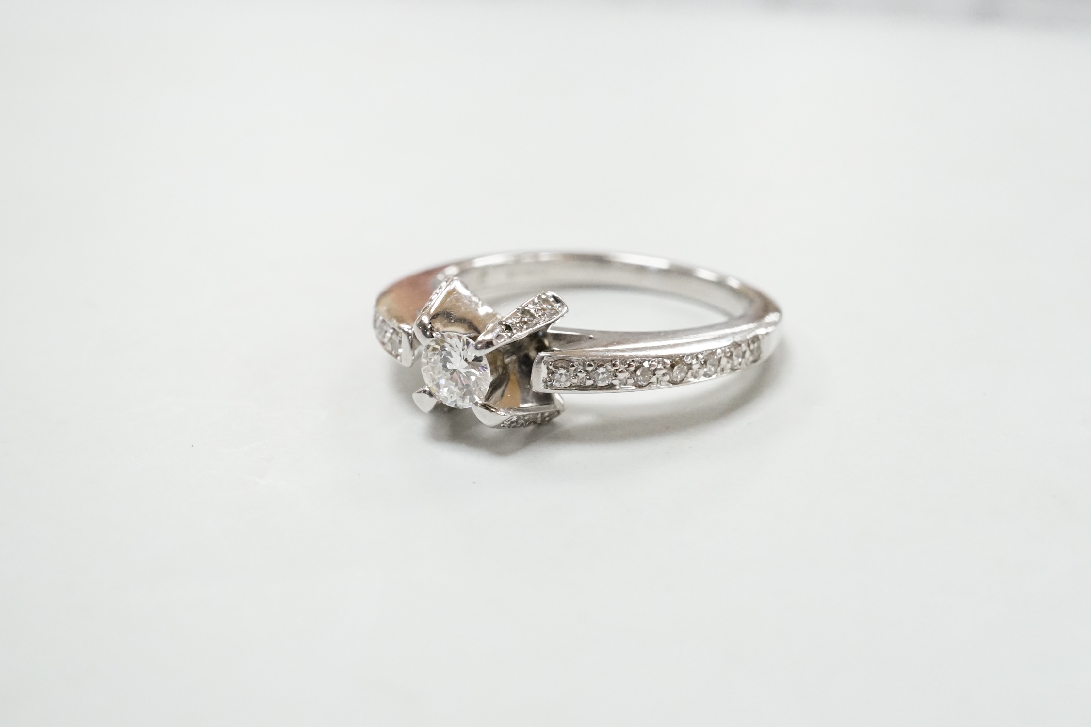 A modern 18ct white gold and claw set single stone diamond ring, with diamond chip set shoulders, size M, gross weight 5.2 grams.